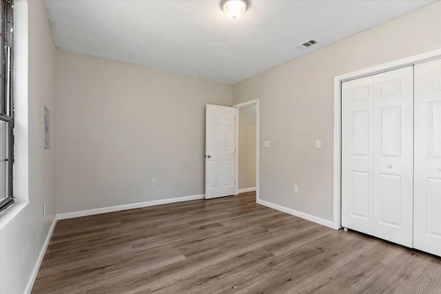 unfurnished bedroom featuring hardwood / wood-style floors, a textured ceiling, and a closet