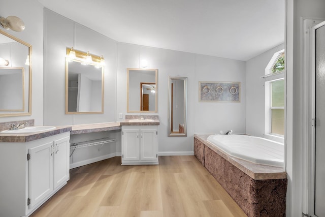 3375 Ben Stoutamire Rd, Tallahassee, FL 32310 - bathroom featuring wood finished floors, two vanities, a bath, and vaulted ceiling