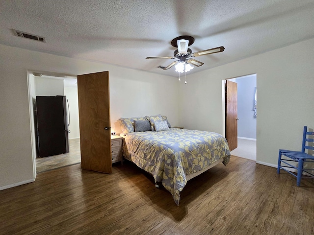 2612 W Tharpe St, Tallahassee, FL 32303 - bedroom with freestanding refrigerator, dark wood-style flooring, a textured ceiling, and ceiling fan