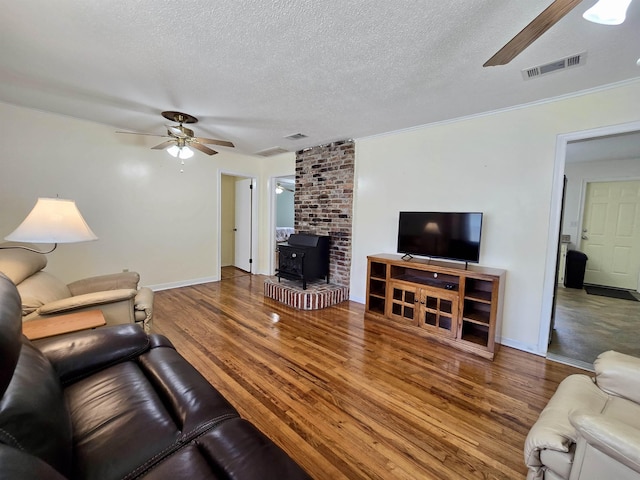 2612 W Tharpe St, Tallahassee, FL 32303 - living room featuring ceiling fan, a wood stove, wood finished floors, and a textured ceiling