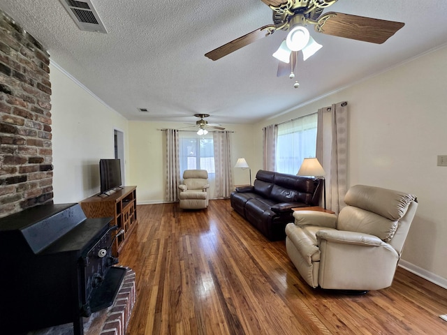 2612 W Tharpe St, Tallahassee, FL 32303 - living room featuring a wood stove, hardwood / wood-style flooring, a ceiling fan, ornamental molding, and a textured ceiling