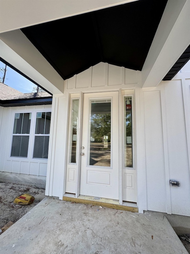 entrance to property with a shingled roof and board and batten siding