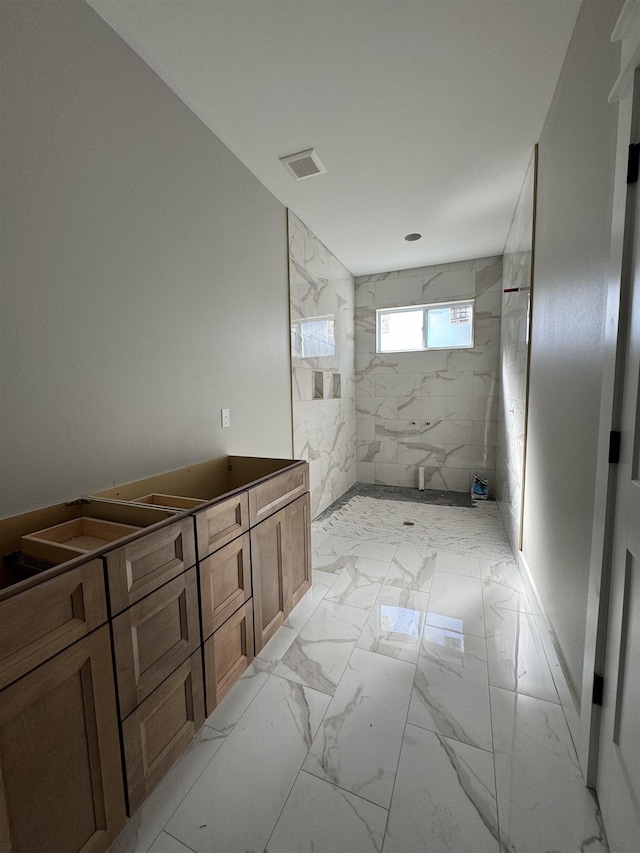 bathroom featuring marble finish floor, a marble finish shower, and visible vents