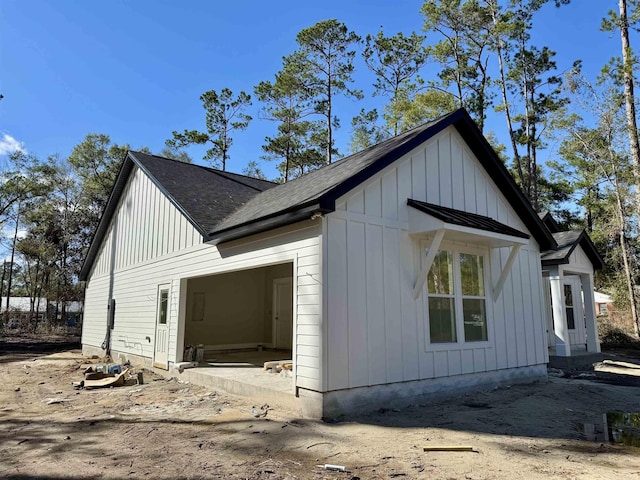 view of side of home with board and batten siding, a standing seam roof, a shingled roof, and metal roof