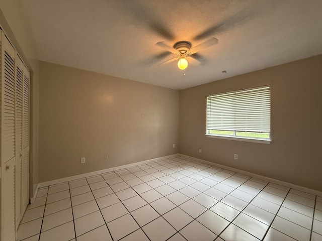 unfurnished bedroom featuring light tile patterned flooring, a closet, and ceiling fan