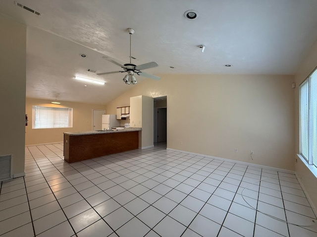 kitchen with ceiling fan, white refrigerator, kitchen peninsula, vaulted ceiling, and light tile patterned flooring