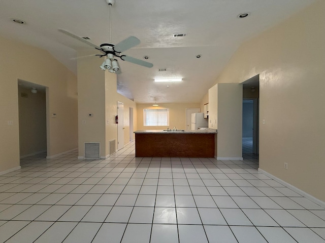 kitchen featuring ceiling fan, white fridge, lofted ceiling, and light tile patterned floors