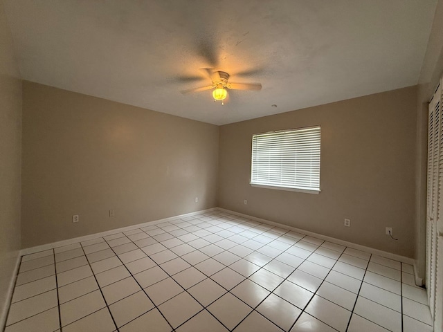 tiled spare room with ceiling fan