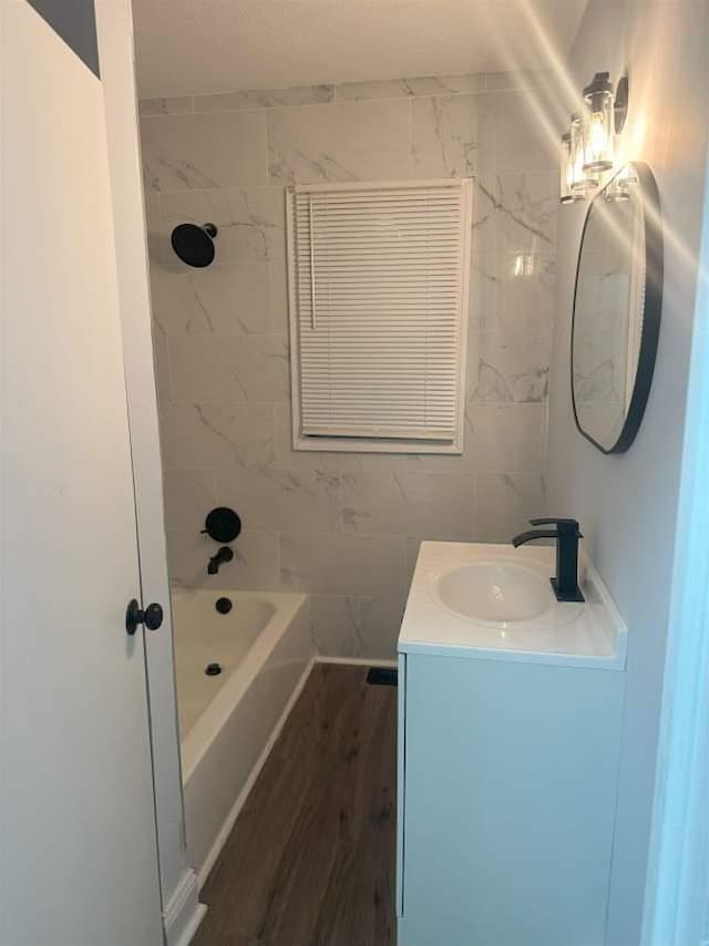 bathroom featuring tile walls, shower / bathing tub combination, wood finished floors, and vanity