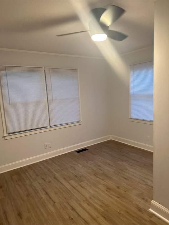 empty room with baseboards, wood finished floors, visible vents, and a ceiling fan