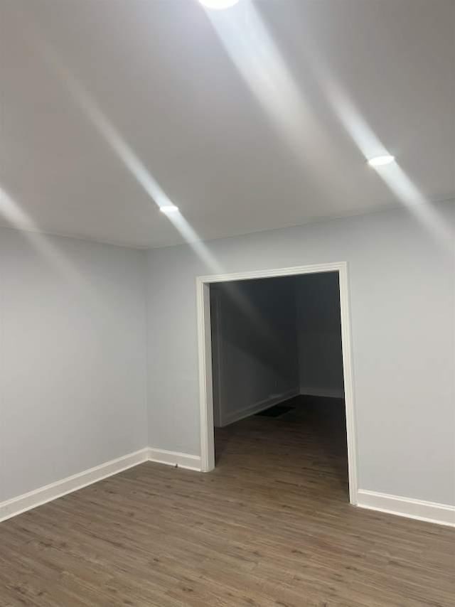 additional living space with baseboards and wood finished floors