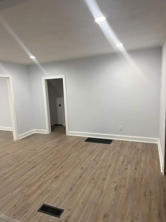 unfurnished room featuring baseboards, visible vents, and wood finished floors