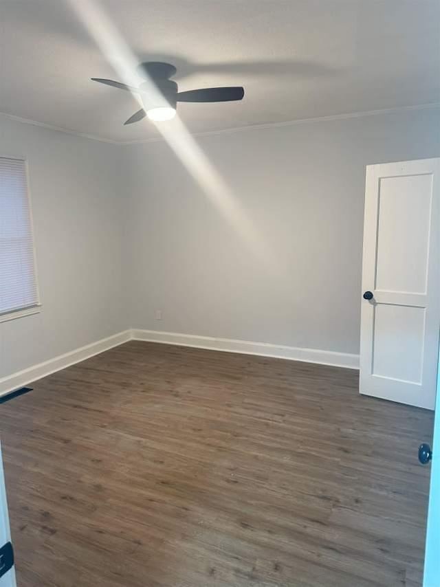 spare room with dark wood-style floors, baseboards, visible vents, and ceiling fan