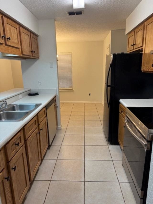 kitchen featuring a textured ceiling, light tile patterned flooring, sink, and stainless steel appliances