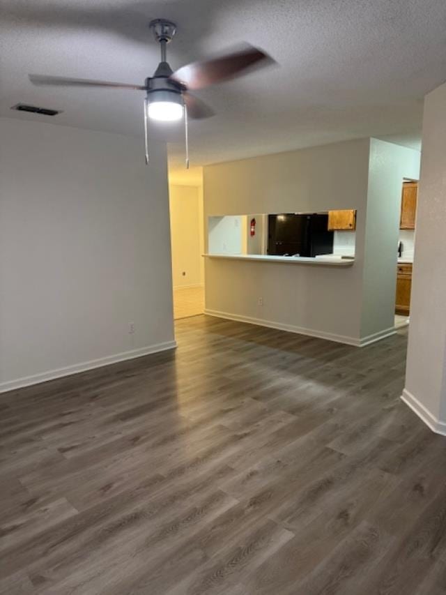 unfurnished living room with dark hardwood / wood-style floors, ceiling fan, and a textured ceiling