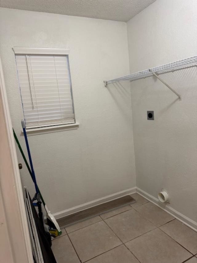 clothes washing area featuring hookup for an electric dryer and tile patterned flooring