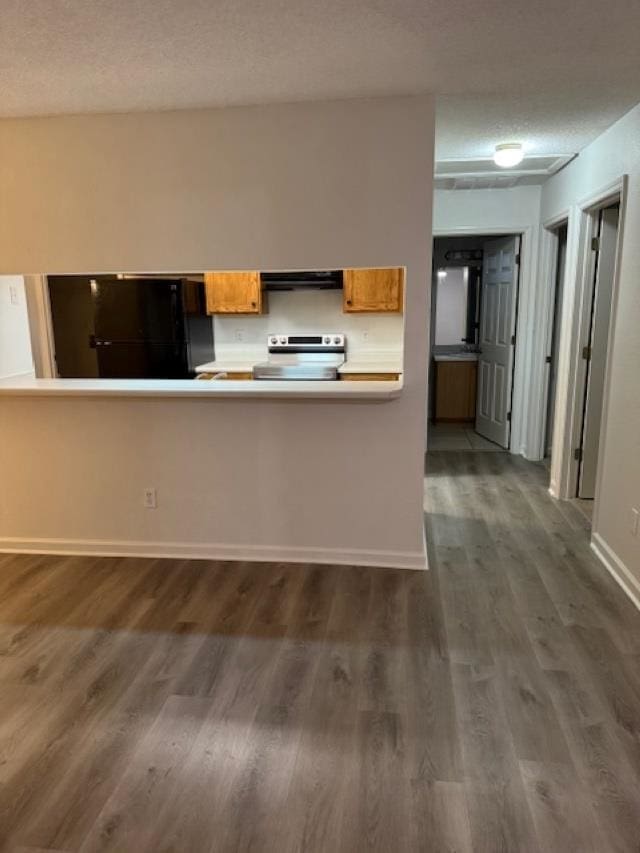 kitchen with electric range, dark hardwood / wood-style flooring, extractor fan, a textured ceiling, and black refrigerator