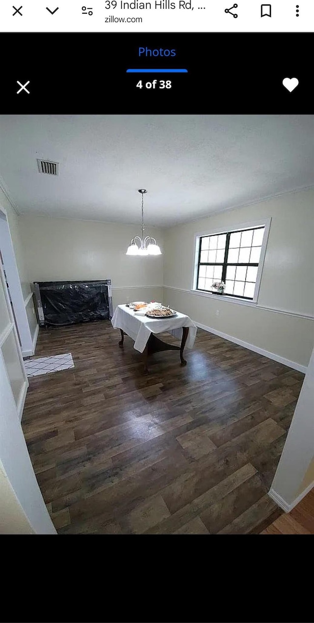 unfurnished dining area with visible vents, dark wood finished floors, baseboards, and an inviting chandelier