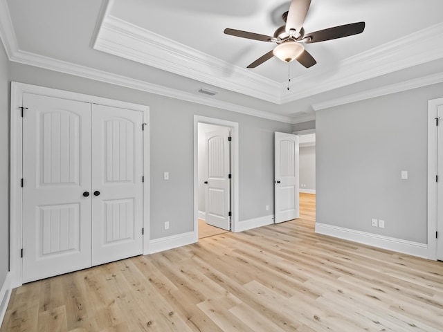 unfurnished bedroom with ceiling fan, ornamental molding, light hardwood / wood-style floors, a raised ceiling, and a closet