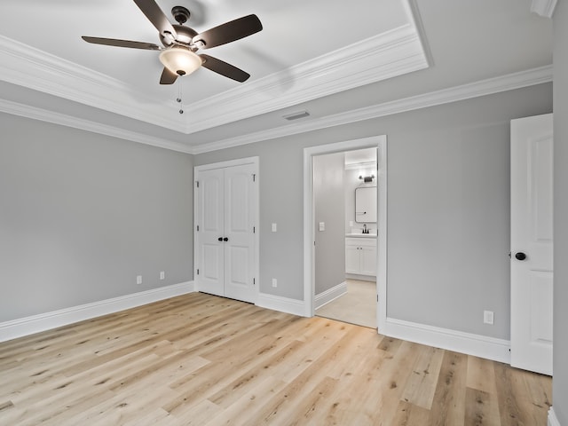 unfurnished bedroom featuring ensuite bathroom, sink, crown molding, light hardwood / wood-style flooring, and ceiling fan