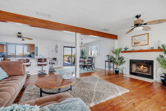 126 Royster Dr, Crawfordville, FL 32327 - living room featuring ceiling fan, beamed ceiling, wood finished floors, a fireplace with flush hearth, and baseboards