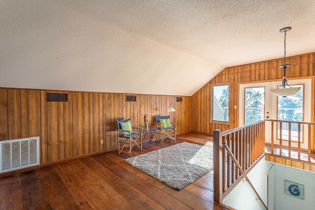 126 Royster Dr, Crawfordville, FL 32327 - sitting room with a textured ceiling, wooden walls, an upstairs landing, vaulted ceiling, and wood-type flooring