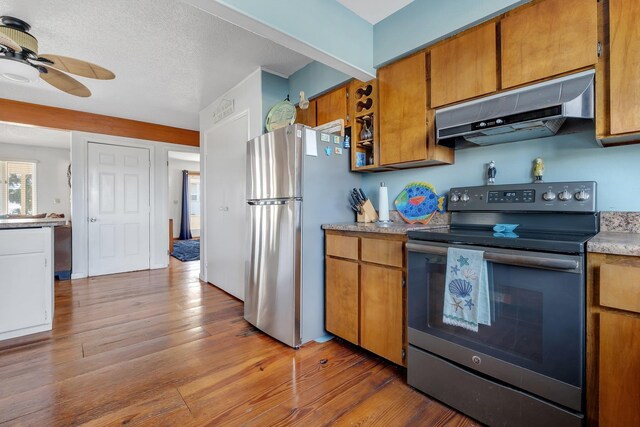 126 Royster Dr, Crawfordville, FL 32327 - kitchen with appliances with stainless steel finishes, under cabinet range hood, brown cabinetry, wood finished floors, and a textured ceiling