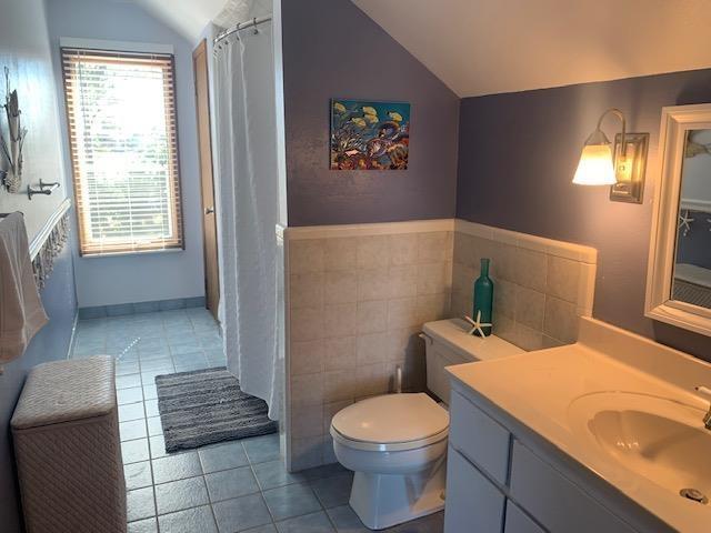 126 Royster Dr, Crawfordville, FL 32327 - full bathroom featuring lofted ceiling, tile patterned floors, toilet, vanity, and tile walls