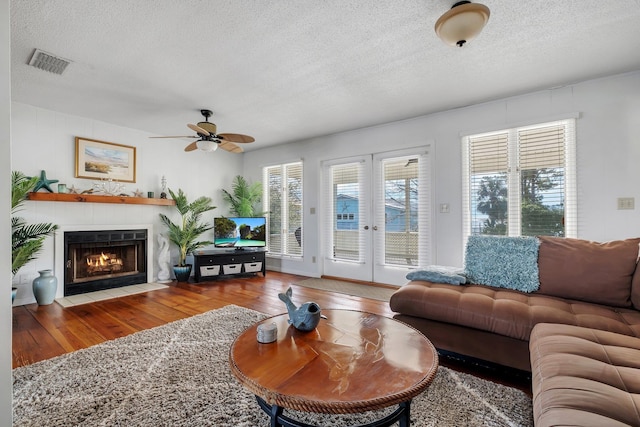 126 Royster Dr, Crawfordville, FL 32327 - living area with wood finished floors, a textured ceiling, french doors, a ceiling fan, and a tile fireplace
