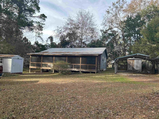 rear view of property featuring a carport, a storage shed, and a lawn