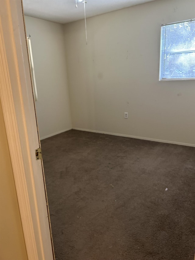 unfurnished room featuring dark colored carpet