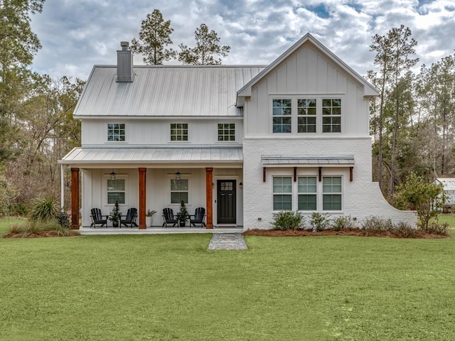 back of house featuring a lawn, ceiling fan, and a patio area