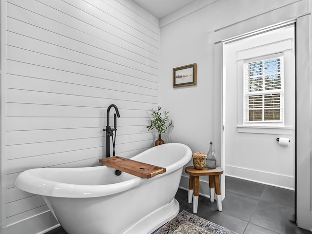 bathroom featuring tile patterned floors, wooden walls, and a bathtub