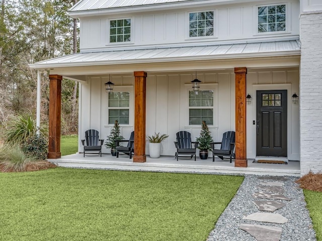 view of exterior entry featuring covered porch and a lawn