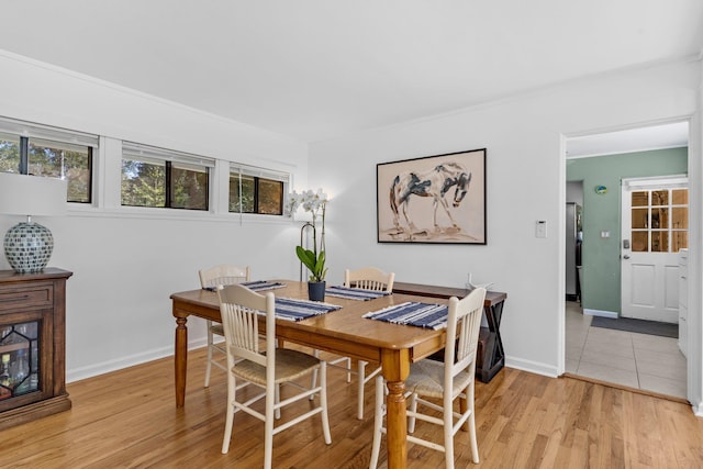 dining space with light wood-type flooring and crown molding