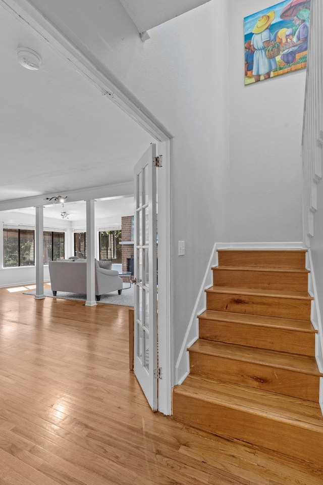 stairway with a fireplace, wood-type flooring, and a healthy amount of sunlight