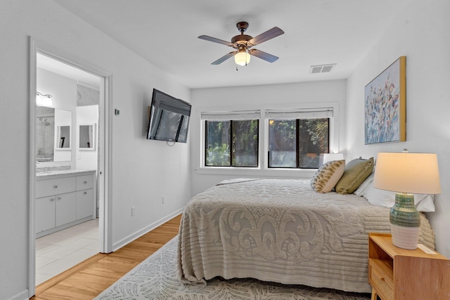 bedroom featuring ensuite bath, light hardwood / wood-style floors, and ceiling fan