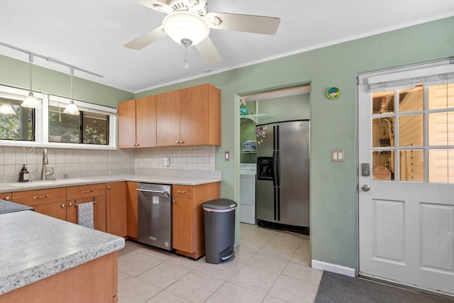 kitchen with tasteful backsplash, light tile patterned flooring, stainless steel appliances, decorative light fixtures, and washer / clothes dryer