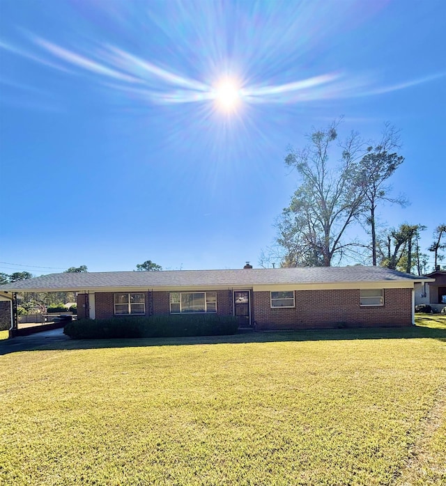 single story home with brick siding, a carport, and a front lawn