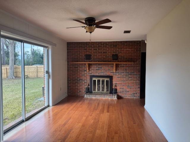 unfurnished living room with ceiling fan, hardwood / wood-style floors, a fireplace, and a textured ceiling