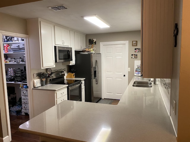 7124 Towner Trce, Tallahassee, FL 32312 - kitchen featuring appliances with stainless steel finishes, white cabinetry, wood finished floors, a peninsula, and light countertops