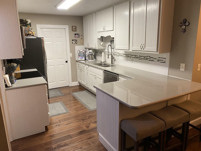 7124 Towner Trce, Tallahassee, FL 32312 - kitchen with dark wood-type flooring, decorative backsplash, a peninsula, white cabinetry, and a breakfast bar
