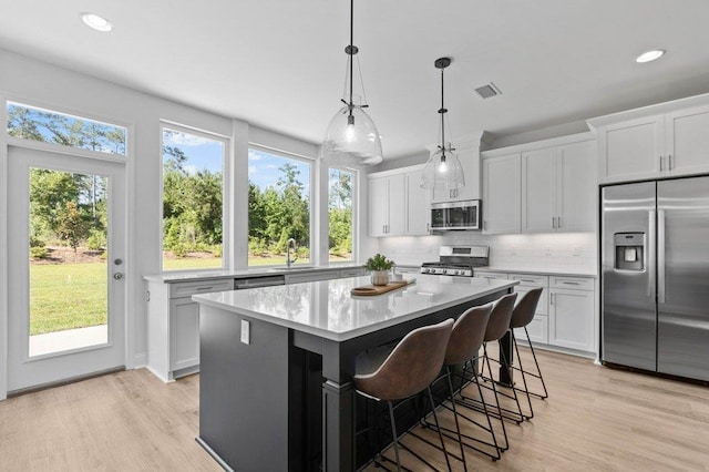 kitchen with plenty of natural light, a center island, appliances with stainless steel finishes, and white cabinets