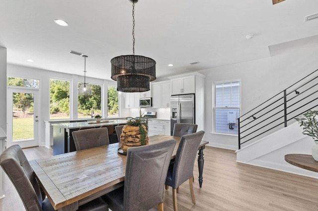 dining space featuring light wood-type flooring, a chandelier, and a healthy amount of sunlight