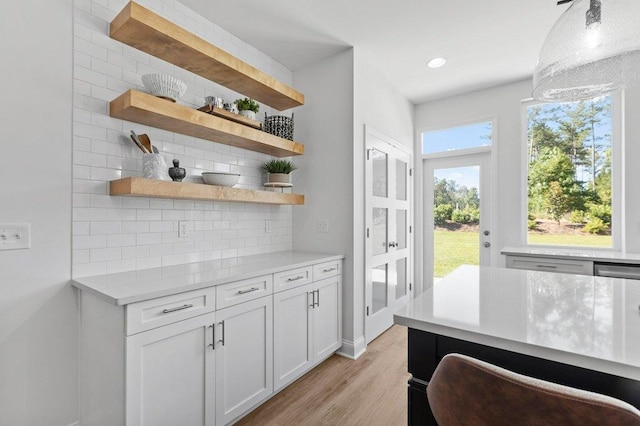 bar featuring white cabinets, light hardwood / wood-style floors, and backsplash