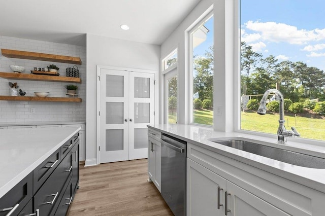 kitchen featuring dishwasher, light wood-type flooring, sink, and white cabinets