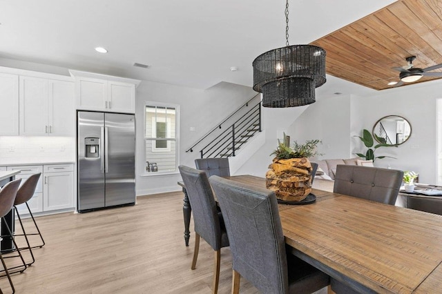 dining space with ceiling fan with notable chandelier and light hardwood / wood-style flooring