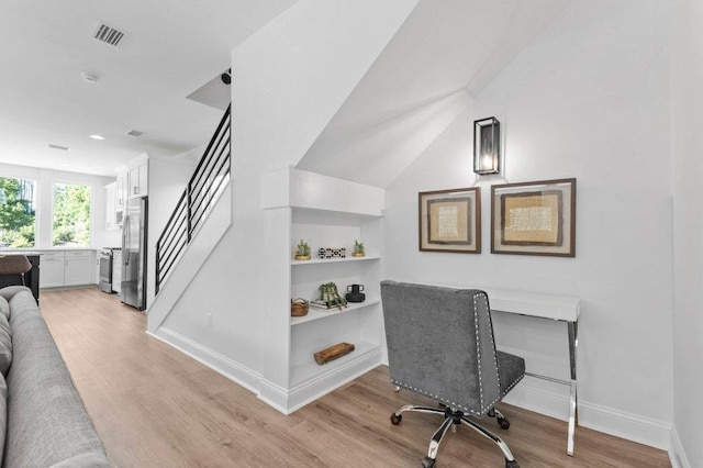 office with light wood-type flooring and lofted ceiling