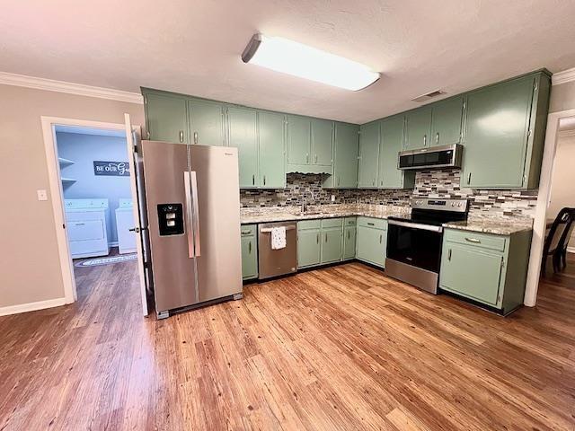 2401 Mexia Ave, Tallahassee, FL 32304 - kitchen featuring appliances with stainless steel finishes, green cabinetry, washer / clothes dryer, light wood finished floors, and crown molding