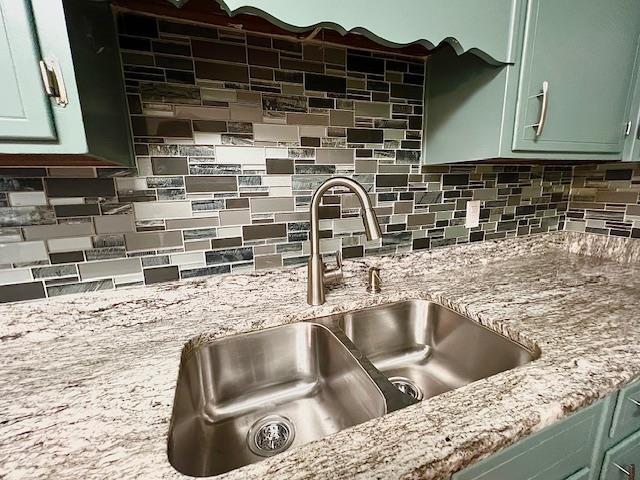 2401 Mexia Ave, Tallahassee, FL 32304 - kitchen view of a sink, green cabinets, backsplash, and light stone counters